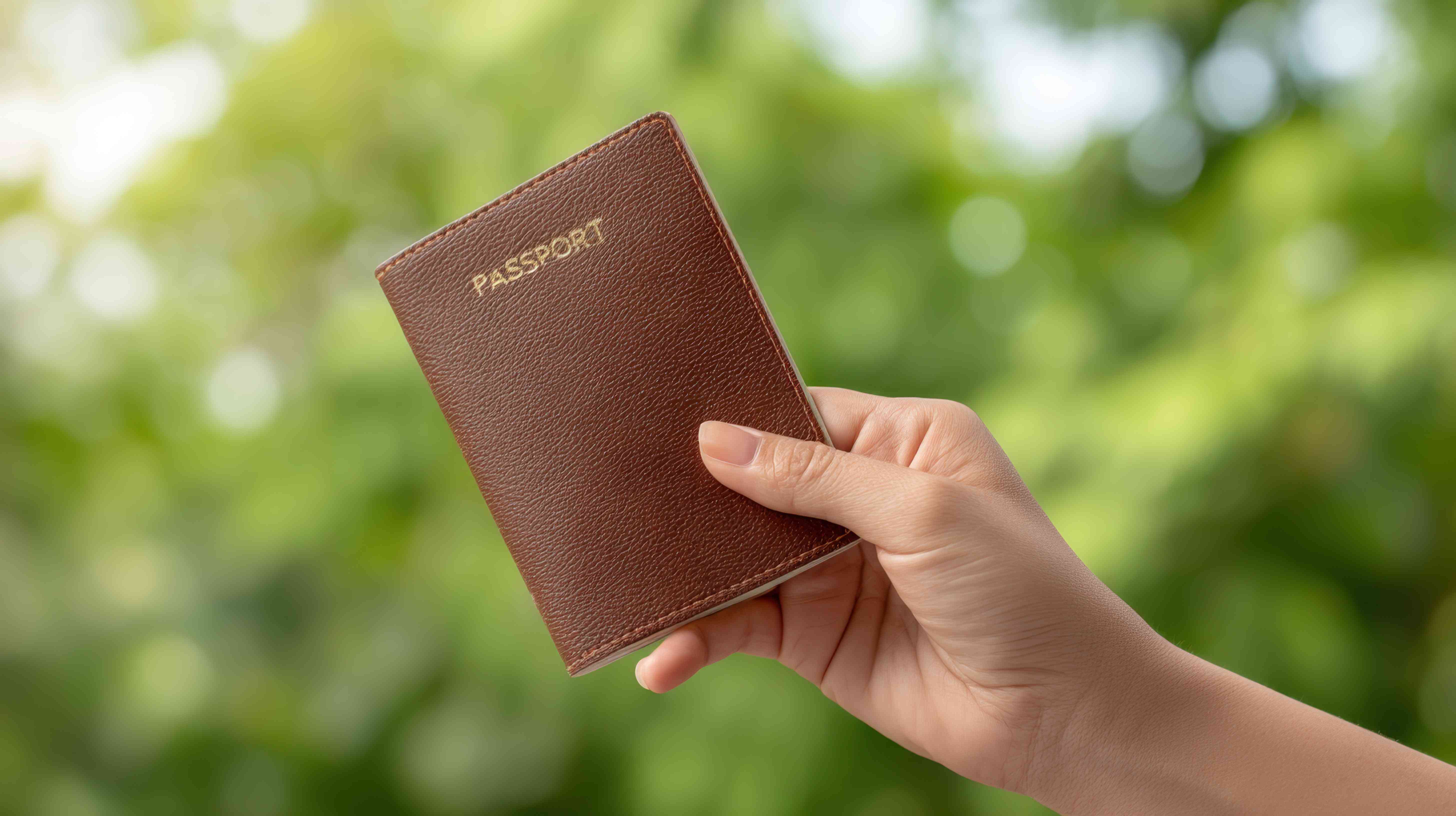 A hand grasps a brown passport