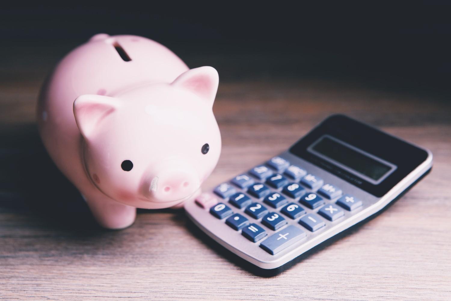 A Piggy Bank And A Calculator On A Table