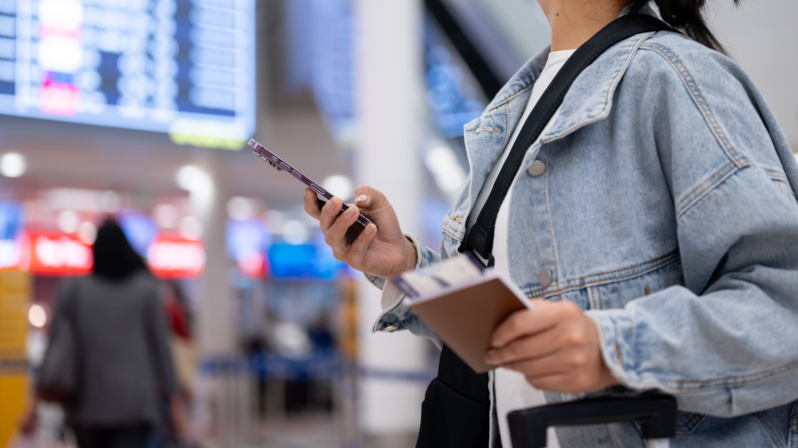 Female standing in the airport terminal with a passport in hand