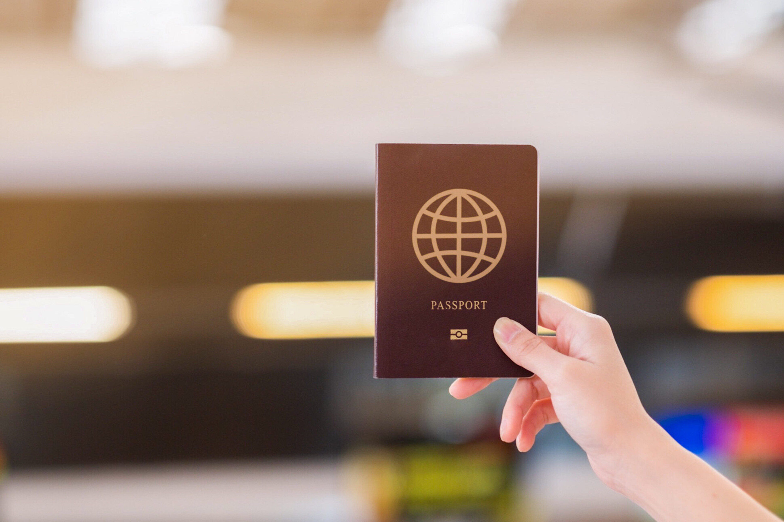 Hand Holding Passport at Airport