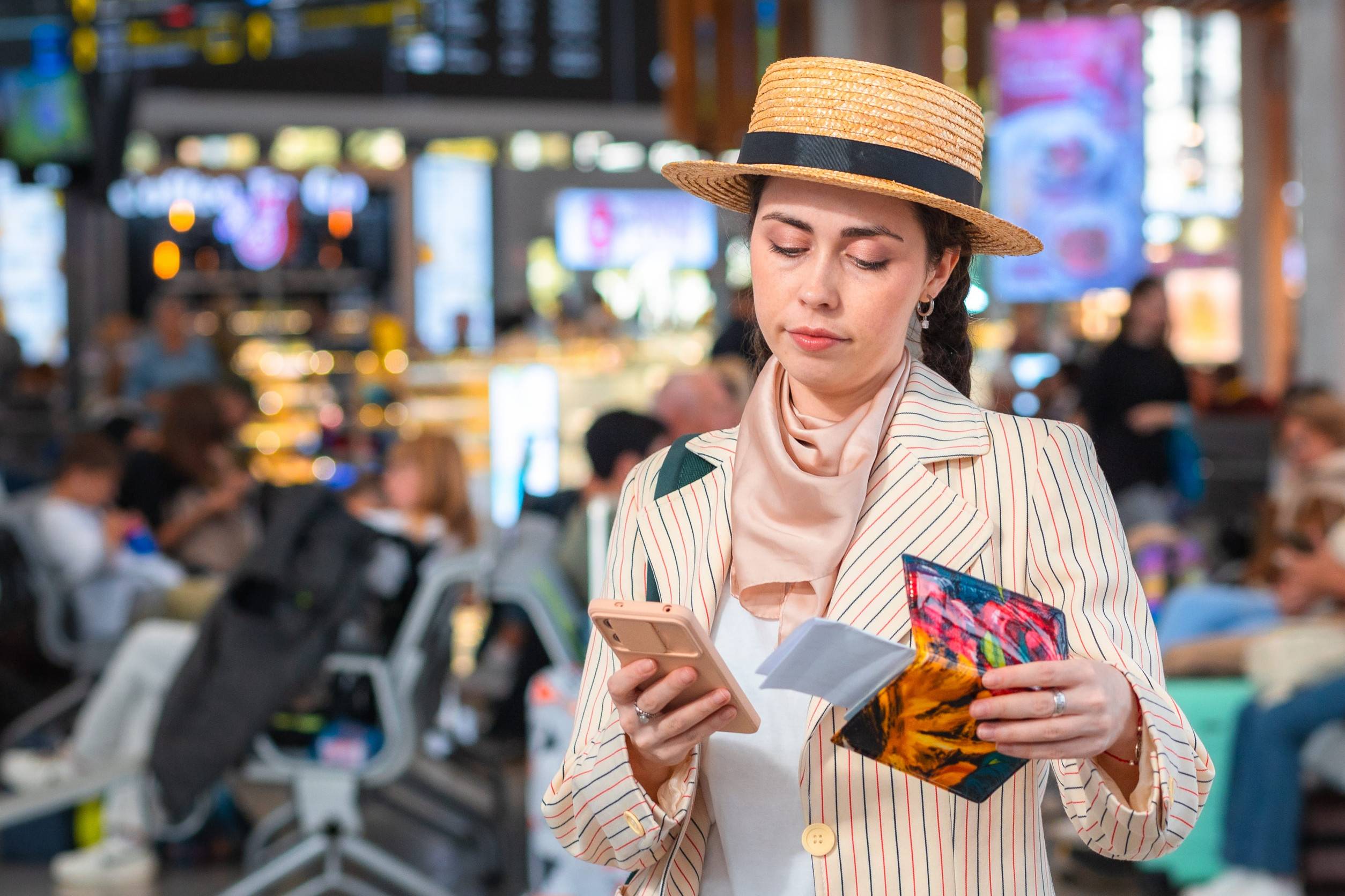 Woman in Straw Hat Holding Passport and Using Smartphone